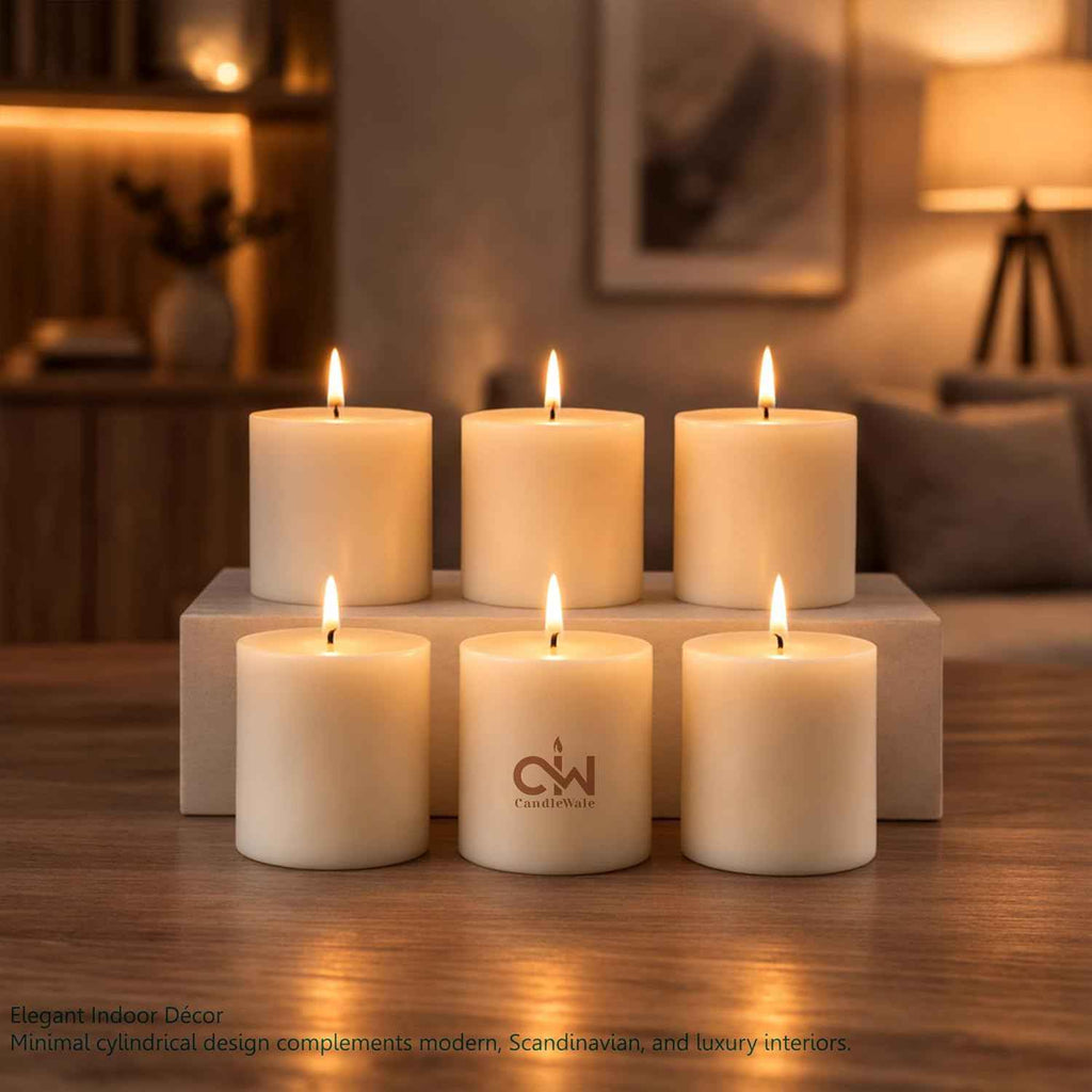Set of 6 lit off-white pillar candles on a white tier, cotton wicks