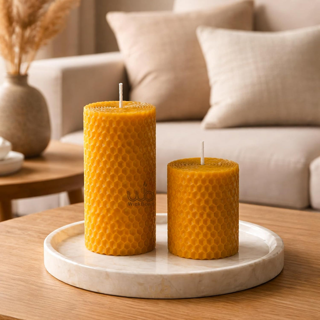 Two unlit honeycomb pillar candles, golden honey color, on a round tray