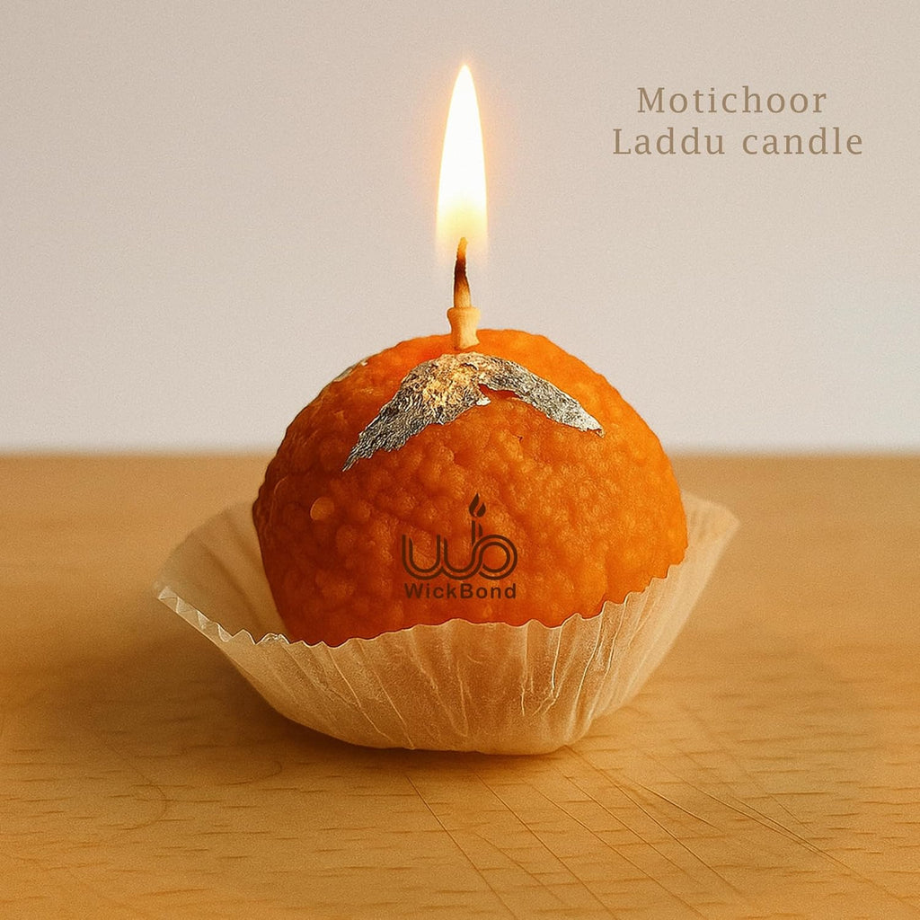 Close-up of lit Motichoor ladoo candle in paper cup, orange textured surface